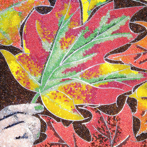 Beaded painting of maple leaves in fall colors and a hand holding the central leaf