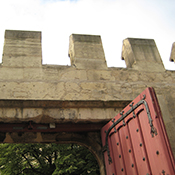A medieval castle wall with crenellations and a heavy wooden door